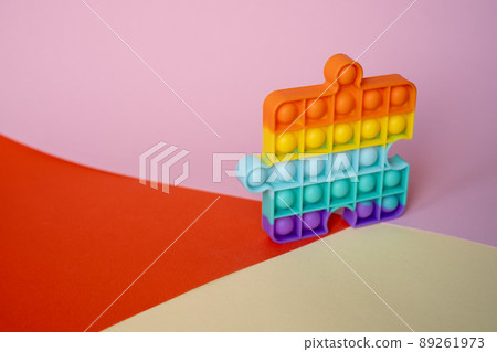 New popular silicone colorful anti-stress popit toy for baby on the background with geometric shapes. simple dimple. Pop it toy New popular silicone colorful anti-stress popit toy for baby on the background with geometric shapes. simple dimple. Pop it toy 89261973