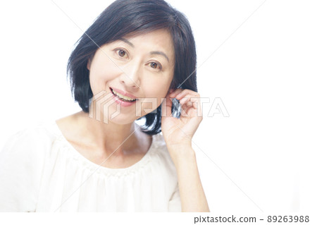 一個微笑著把手放在耳邊的中年婦女 一個微笑著把手放在耳邊的中年婦女 89263988