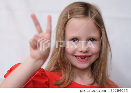 Smiling little girl without front teeth gesture two fingers up 89264055