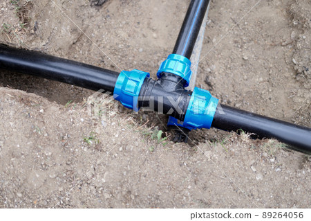 Installed PVC water pipes are assembled and laid in trench at construction site 89264056