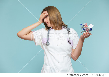 high price of drugs and medicine. Inflation, imitation. A woman doctor shows a miniature basket of medicines, on a blue background. Copy paste. healthcare concept. high price of drugs and medicine. Inflation, imitation. A woman doctor shows a miniature basket of medicines, on a blue background. Copy paste. healthcare concept. 89266616