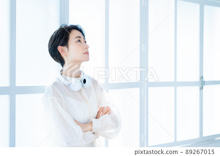 Middle-aged woman wearing headphones around her neck 89267015