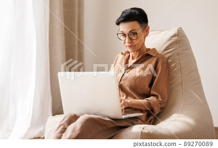 Middle aged woman using laptop at home Middle aged woman using laptop at home 89270089
