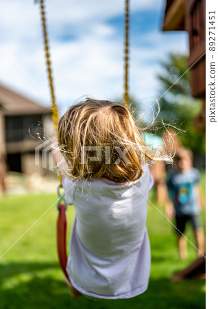 Young Caucasian girl on a swing with long blond hair blowing in the wind Young Caucasian girl on a swing with long blond hair blowing in the wind 89271451