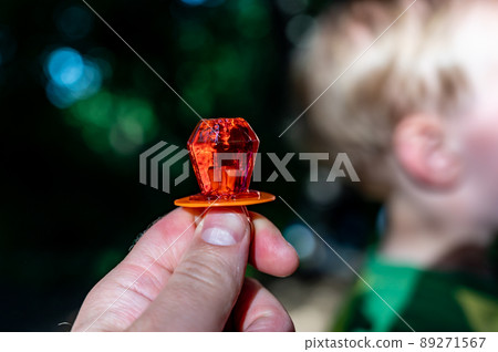 Diamond shaped ring sucker candy being held up with a child defocused in the background 89271567