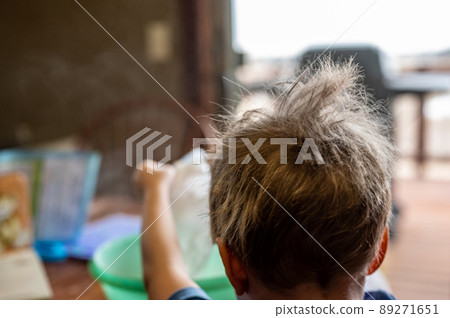 Young male boy helping in the kitchen with messy hair sticking up Young male boy helping in the kitchen with messy hair sticking up 89271651