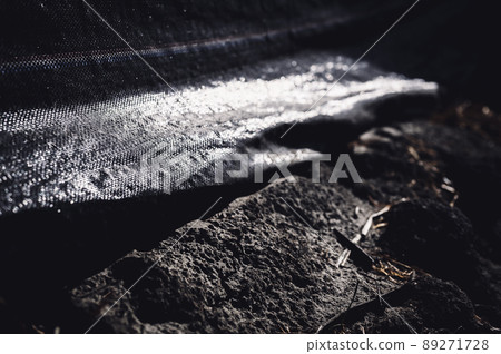 Selective focus on silt fence filter fabric along contact with soil. Selective focus on silt fence filter fabric along contact with soil. 89271728
