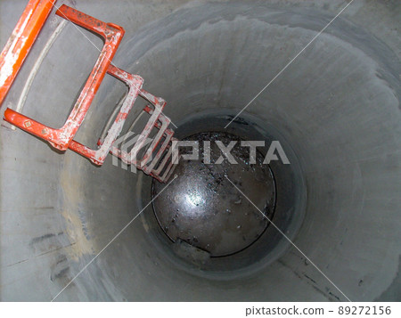 Looking into an open concrete manhole with step rungs leading down stagnant water Looking into an open concrete manhole with step rungs leading down stagnant water 89272156