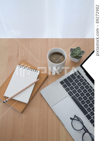 Simple workplace with laptop computer, coffee cup, notepad and eyeglasses on wooden table. Flay lay. Simple workplace with laptop computer, coffee cup, notepad and eyeglasses on wooden table. Flay lay. 89272982