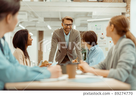 Happy man talking to his female colleague during a meeting Happy man talking to his female colleague during a meeting 89274770
