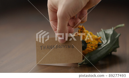 man put thanhksgiving card next to decorative pumpkins on wood table man put thanhksgiving card next to decorative pumpkins on wood table 89277493