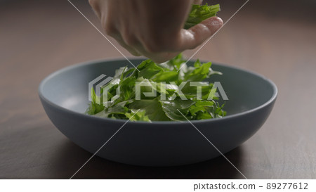 making salad, arrangfe frisee lettuce in blue bowl on wood table 89277612