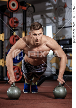 Man doing push-up exercise with dumbbell 89277676