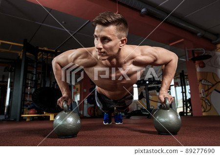 Man doing push-up exercise with dumbbell 89277690