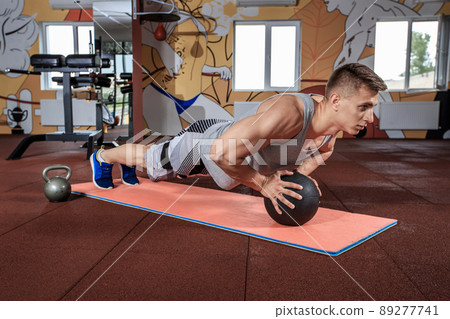 Attractive male athlete performing push-ups on medicine ball Attractive male athlete performing push-ups on medicine ball 89277741