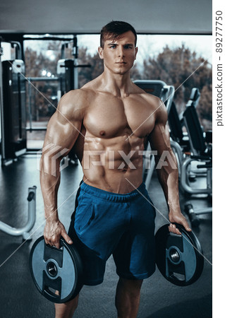 Portrait of a handsome man resting near bar in fitness gym and looking at the camera Portrait of a handsome man resting near bar in fitness gym and looking at the camera 89277750