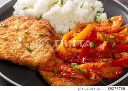 Closeup of delicious fried breaded meat Gypsy Schnitzel with spicy pepper sauce served with rice as traditional German fast food in a plate. Horizontal Closeup of delicious fried breaded meat Gypsy Schnitzel with spicy pepper sauce served with rice as traditional German fast food in a plate. Horizontal 89278766