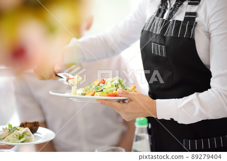 Waiter carrying plates with salad on some festive event, party or wedding reception. Staff of restaurant or cafe. Waiter carrying plates with salad on some festive event, party or wedding reception. Staff of restaurant or cafe. 89279404