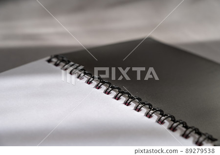 Black spring-loaded notebook against a gray background. Close-up of an open notebook and blank white sheets. Black spring-loaded notebook against a gray background. Close-up of an open notebook and blank white sheets. 89279538