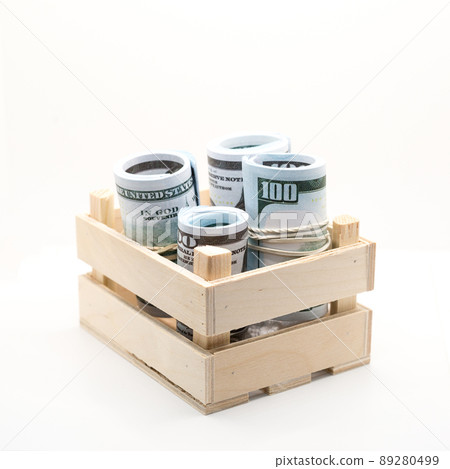 Dollars rolled into a roll and tied with a colored elastic band in a wooden box 89280499