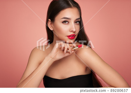 A beautiful young woman applying lipstick A beautiful young woman applying lipstick 89280637