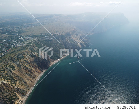Aerial view from above on calm azure sea and volcanic rocky shores. Small waves on water surface in motion blur. Nature summer ocean sea beach background. Nobody. Holiday, vacation and travel concept 89280701