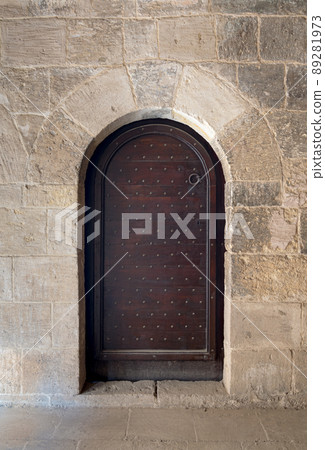 Wooden aged vaulted ornate door and stone wall Wooden aged vaulted ornate door and stone wall 89281973
