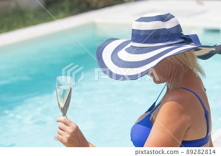 Beautiful woman is holding champagne glass in the pool. Beautiful woman is holding champagne glass in the pool. 89282814