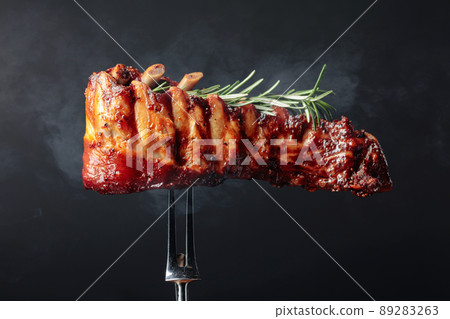 Grilled pork ribs with rosemary on a fork. Grilled pork ribs with rosemary on a fork. 89283263
