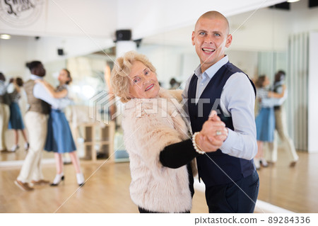 Man and elderly woman performing ballroom dance in dancing room 89284336