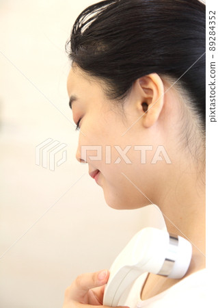 A woman who seems to be comfortable hitting a facial device A woman who seems to be comfortable hitting a facial device 89284352