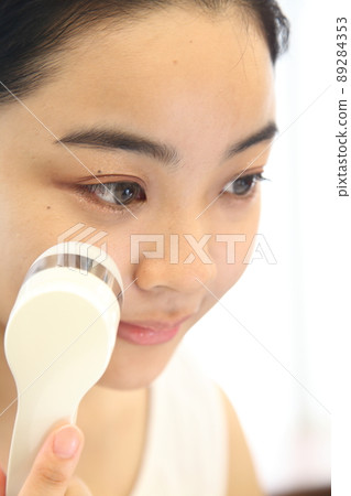 A woman who seems to be comfortable hitting a facial device 89284353