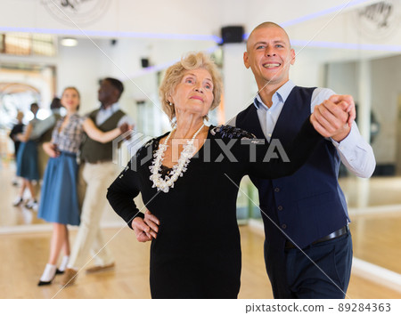 Elderly woman learning ballroom dancing movements in pair 89284363