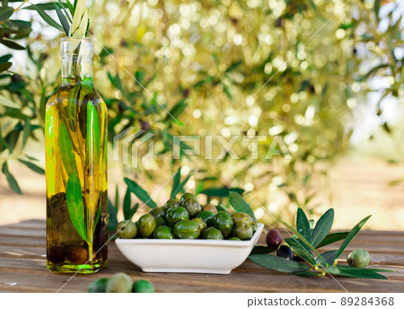 green olives and oil on table in olive grove 89284368