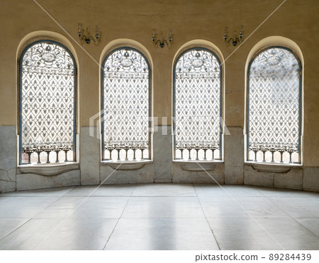 Windows with iron decorated grid, yellow wall, and marble floor Windows with iron decorated grid, yellow wall, and marble floor 89284439
