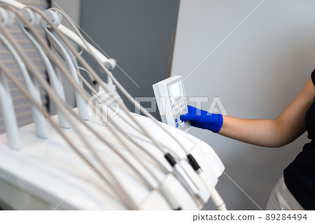 Dentist hand in glove press the control buttons of dental chair Dentist hand in glove press the control buttons of dental chair 89284494