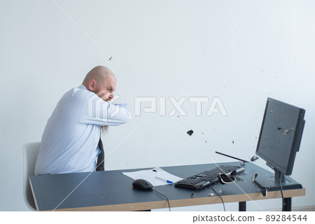 Angry bald man with a red beard in the office in a business suit crashes a computer. Manager with a nervous breakdown breaks the keyboard on the monitor. 89284544