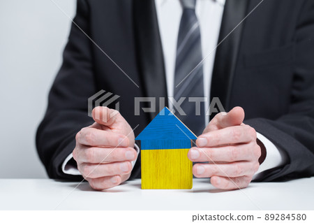 Save Ukraine concept. A man protects the house with the flag of Ukraine 89284580