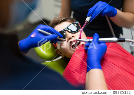 Dentist and assistant make preventive dental plaque cleaning for teenager 89285332