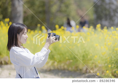 Young woman taking pictures of flowers with a camera 89286346