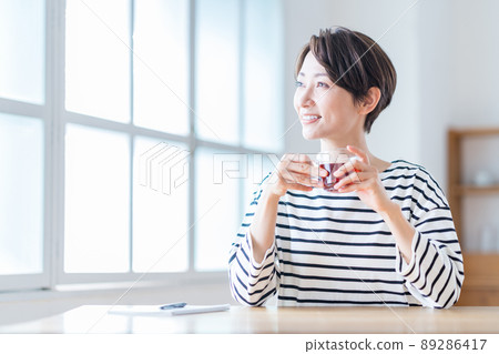 A middle-aged woman taking a break in the living room. A middle-aged woman taking a break in the living room. 89286417