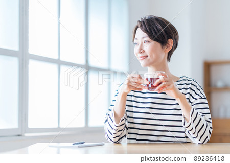 A middle-aged woman taking a break in the living room. A middle-aged woman taking a break in the living room. 89286418