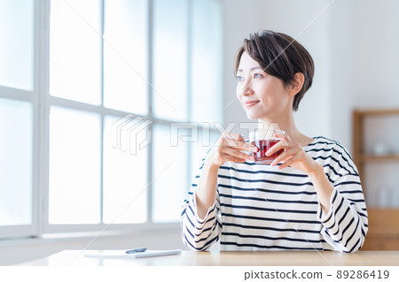 A middle-aged woman taking a break in the living room. A middle-aged woman taking a break in the living room. 89286419