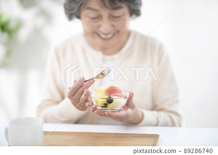 Senior woman eating fruit 89286740