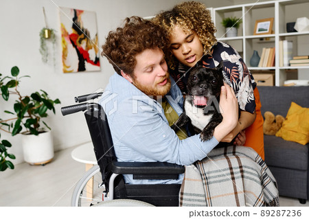 African young girl giving small dog to man with disability for his quickly rehabilitation 89287236