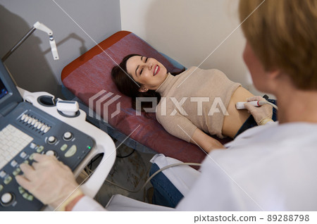 Charming woman smiling at her attending doctor while checking her health during an ultrasound examination in a medical clinic. ultrasonography USG Charming woman smiling at her attending doctor while checking her health during an ultrasound examination in a medical clinic. ultrasonography USG 89288798