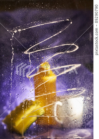 Close-up of household cleaning products and kitchen accessories. A plastic cup and a bottle with a sponge on a lilac background. View through dirty glass. High quality photo 89290790