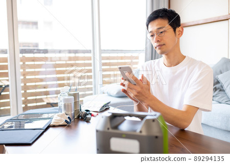 A man collecting information while charging his smartphone using a portable power supply 89294135