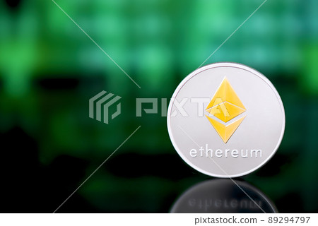 Silver Ethereum coin with a golden symbol on green digital background.  89294797