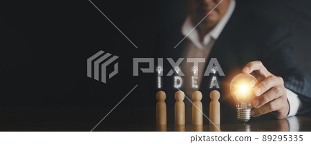 Hand man holding light bulb with text i d e a and wooden doll. Innovation idea and knowledge concept. Hand of businessman holding light bulb with wooden doll Hand man holding light bulb with text i d e a and wooden doll. Innovation idea and knowledge concept. Hand of businessman holding light bulb with wooden doll 89295335